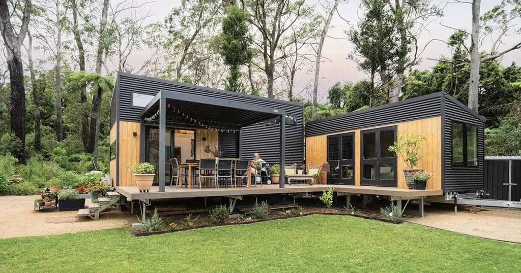Modern tiny home with outdoor deck surrounded by lush greenery in Australia.